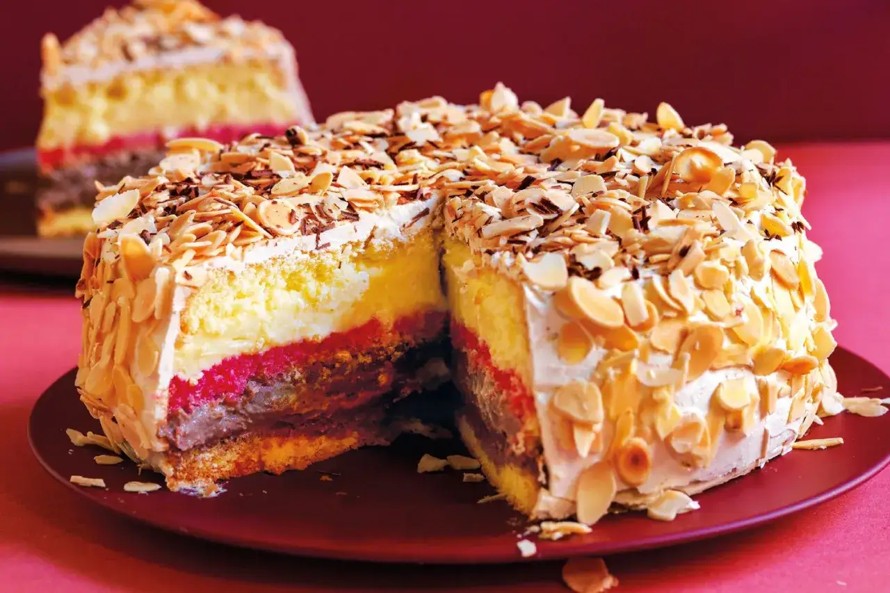 Una fetta di pizza dolce abruzzese, stratificata con crema, confettura e cioccolato, ricoperta di mandorle a lamelle.