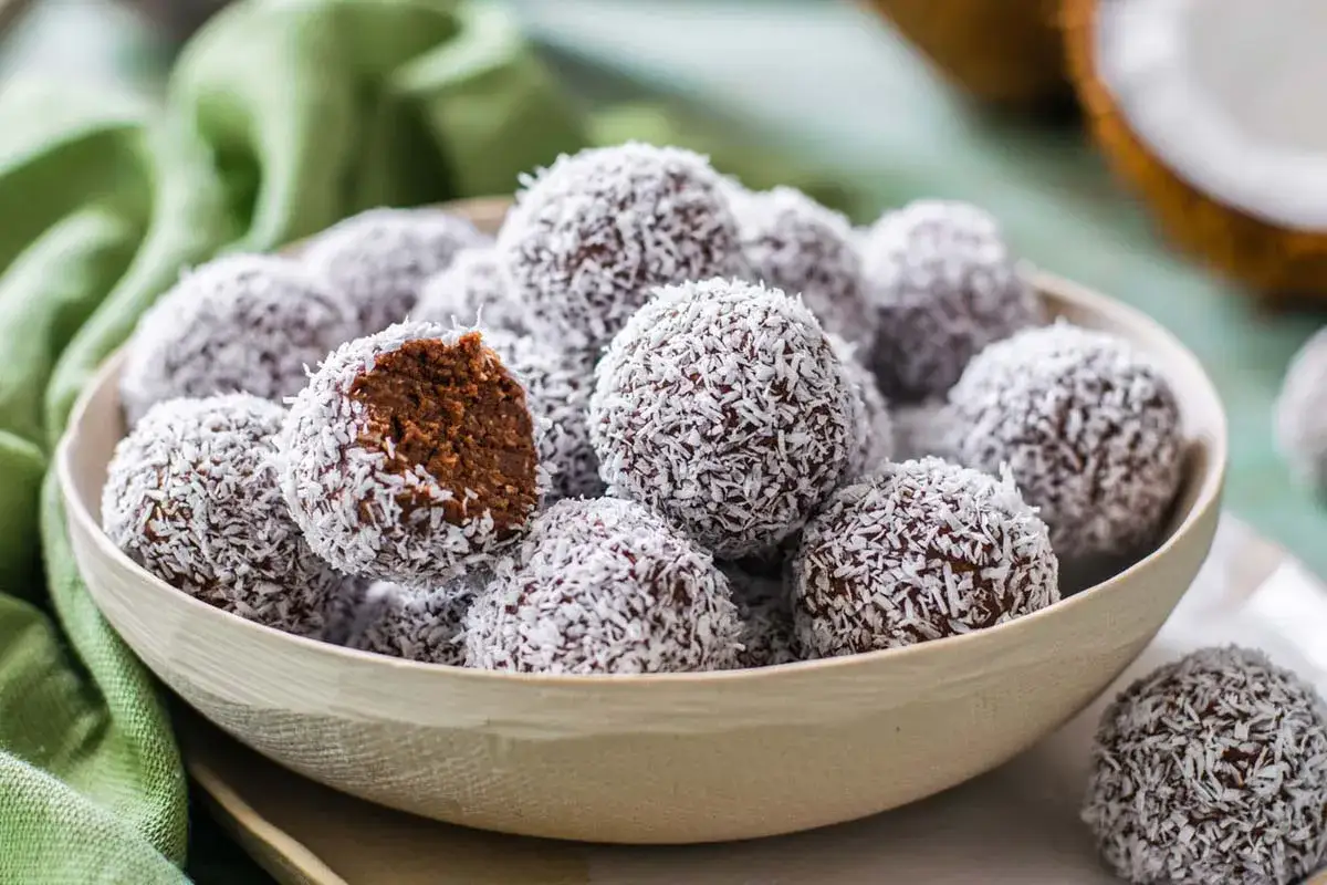 Una ciotola piena di golose palline di cocco, alcune con un morso rivelatore che mostra il ripieno al cioccolato.