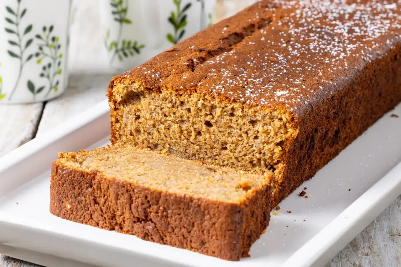 Delizioso banana bread senza burro, spolverato di zucchero a velo, pronto per essere gustato.