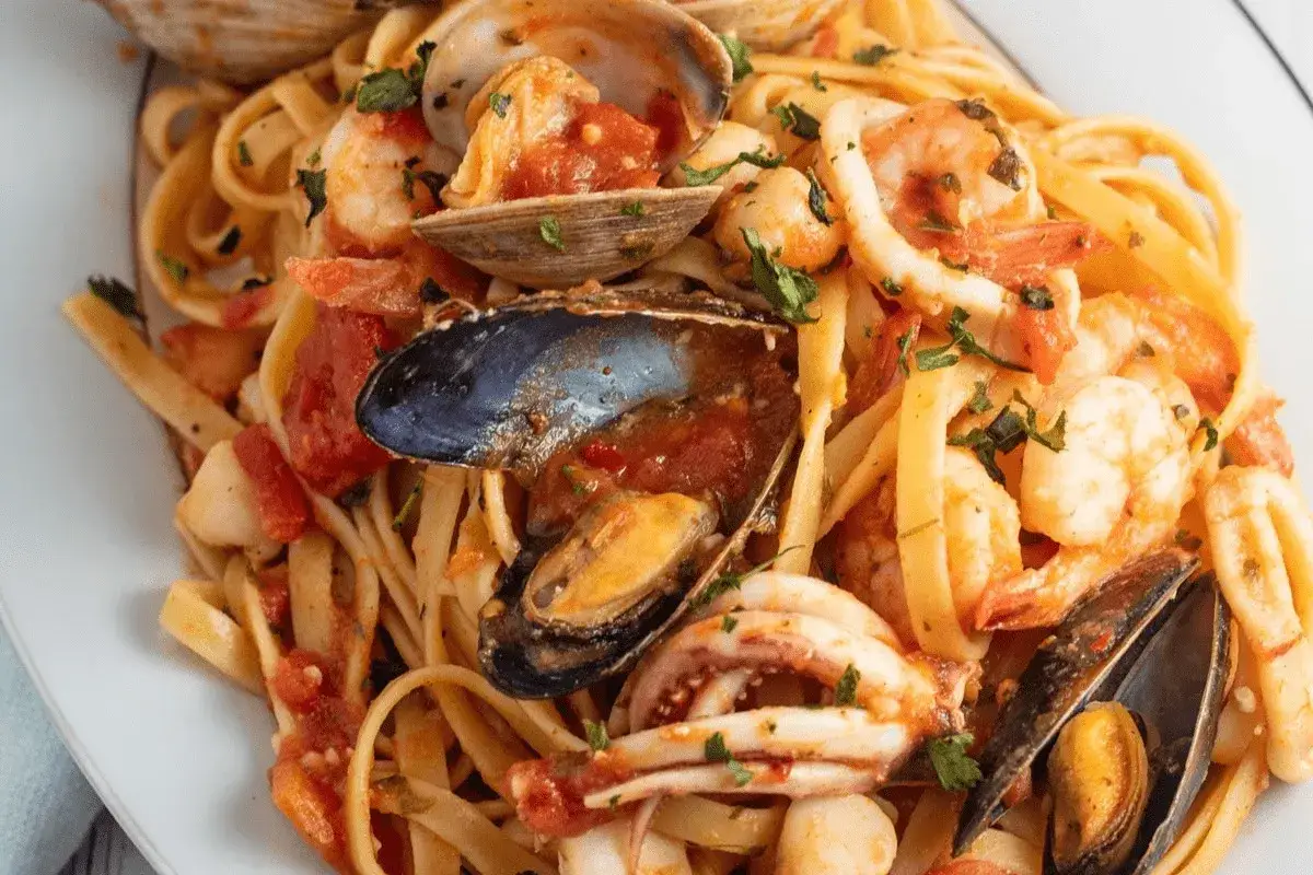 Un piatto invitante di scialatielli ai frutti di mare, con gamberi, cozze, vongole e calamari in un sugo rosso.