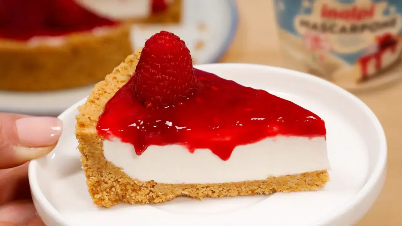 Fetta di cheesecake con mascarpone, base croccante, ripieno cremoso e topping ai lamponi con un frutto intero.