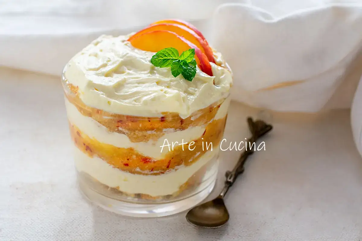 Delizioso tiramis&ugrave; alle pesche in coppetta, con strati di crema e frutta fresca, guarnito con fettine di pesca e foglioline di menta.