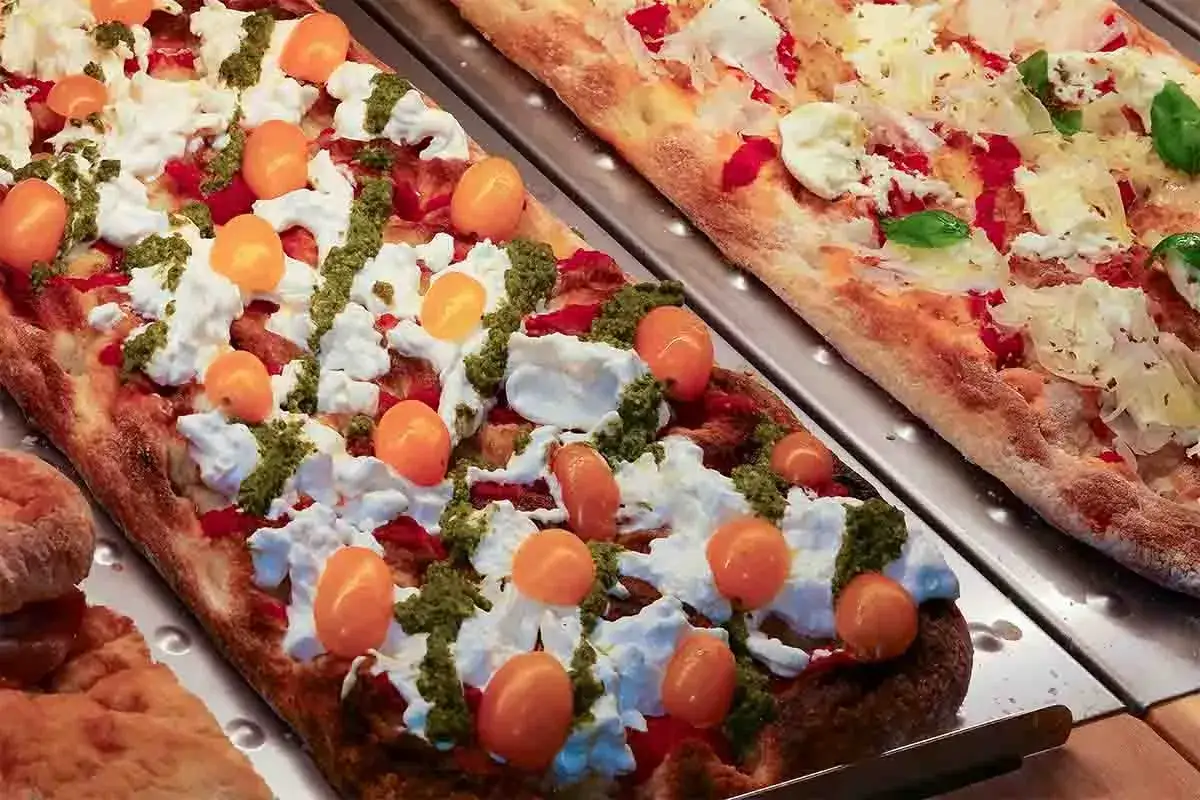 Pizza bianca con pomodorini, mozzarella e pesto. Un tripudio di sapori freschi e colorati, perfetta per un pranzo veloce.