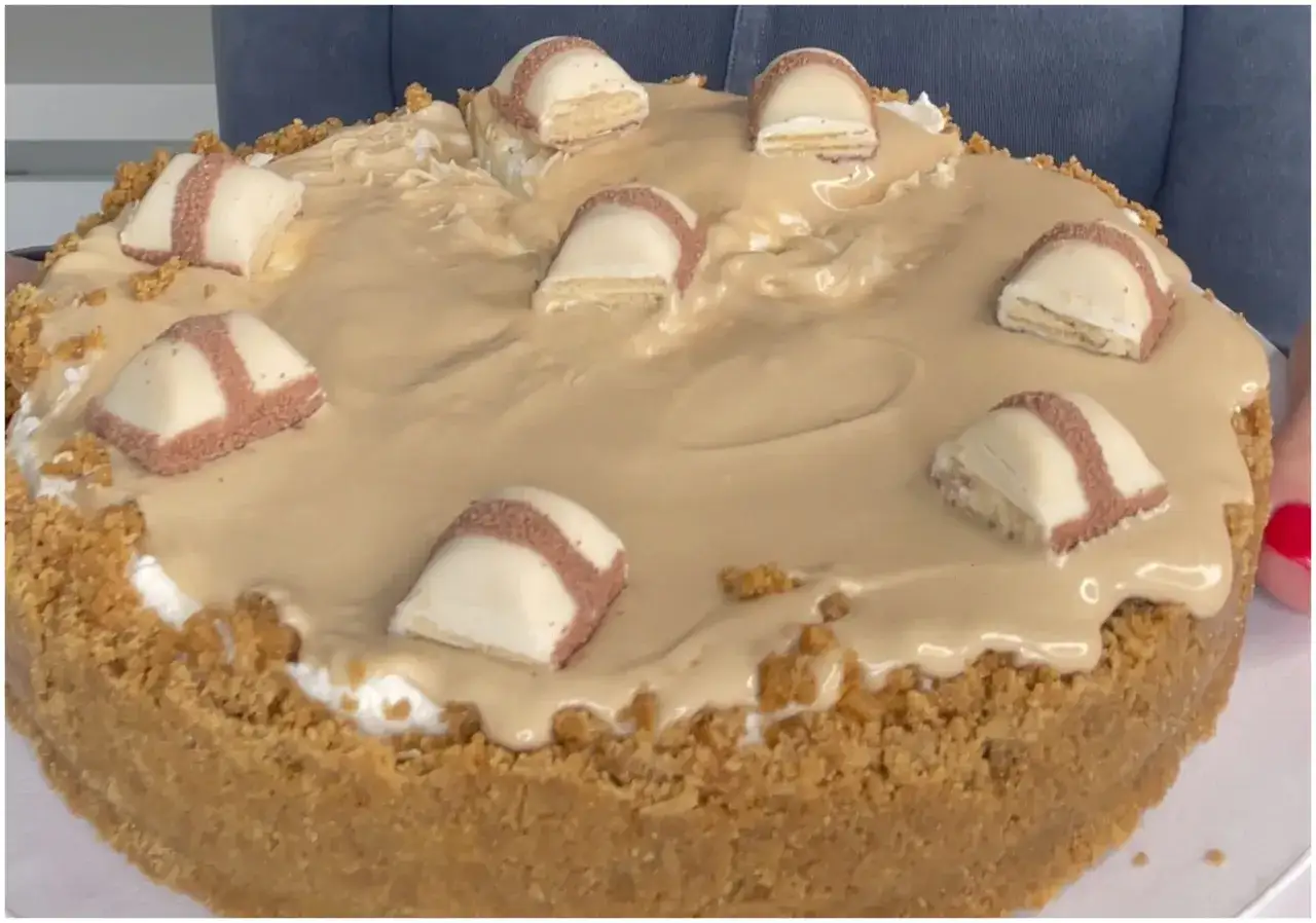 Cheesecake kinder con base croccante, ripieno cremoso e copertura al caramello, decorata con pezzi di cioccolato.