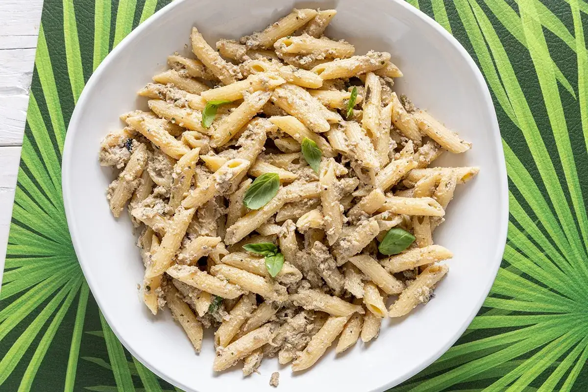 Penne cremose condite con un sugo saporito, guarnite con basilico fresco. Un'ottima pasta fredda senza pomodori, perfetta per l'estate.