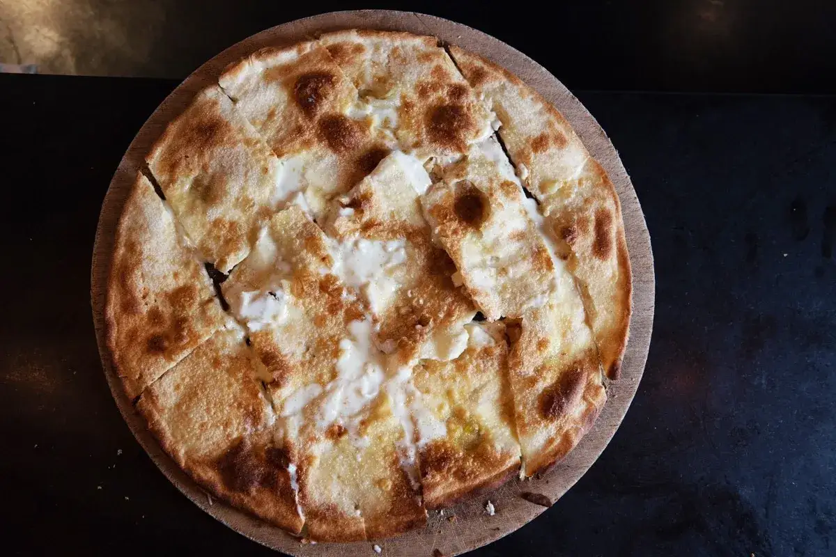 Focaccia di Recco ricetta: sottile e croccante, con un ripieno filante di formaggio fresco. Perfetta per un pranzo veloce.