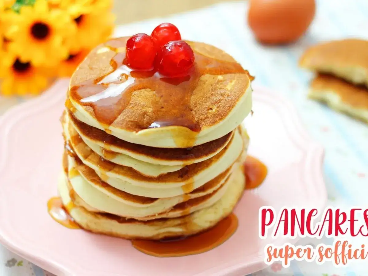 Pancakes soffici, una deliziosa ricetta per iniziare la giornata con dolcezza. Guarniti con sciroppo e ciliegie.