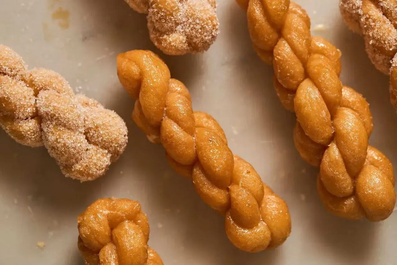 Dolci intrecciati dorati, alcuni ricoperti di zucchero, ricordano la mazza frissa, una delizia da gustare.