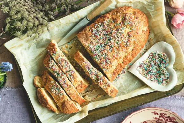 Ciambella romagnola, soffice e profumata, decorata con zuccherini colorati. Una fetta invitante, pronta per essere gustata.