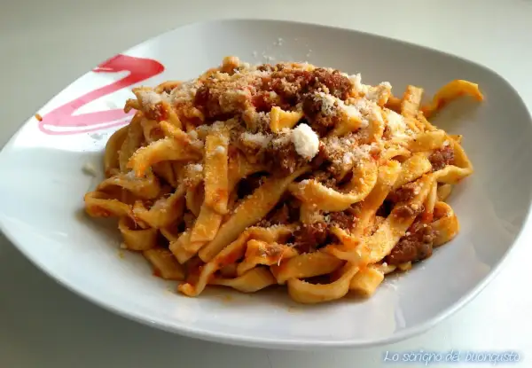 Un piatto invitante di tagliatelle al ragù, condite con abbondante parmigiano grattugiato.