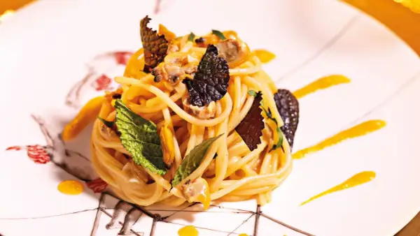 Spaghetti con frutti di mare, guarniti con foglie di menta e scaglie di tartufo. Un'idea su come cucinare la pasta in modo elegante.