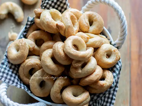 Un cesto pieno di taralli pugliesi ricetta originale, dorati e croccanti, pronti per essere gustati.