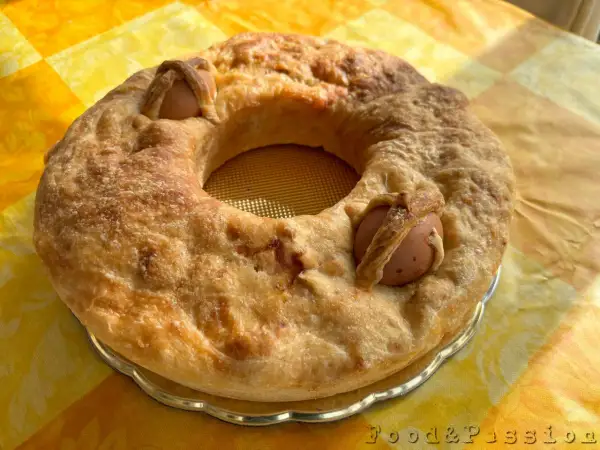 Casatiello napoletano dorato, con uova intere incastonate nell'impasto, pronto per essere gustato.