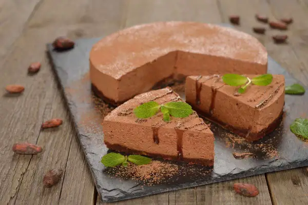 Deliziosa bavarese al cioccolato, spolverata di cacao e decorata con menta fresca. Un dolce invitante su una lavagna scura.