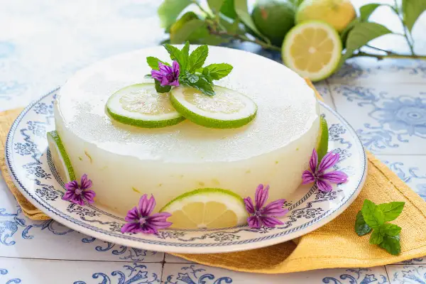 Delizioso gelo di limone decorato con fette di limone, fiori viola e foglie di menta.
