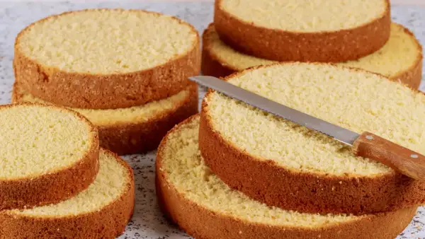 Dischi di pan di spagna dorati e soffici, pronti per essere farciti. Un coltello da torta è appoggiato su uno strato.