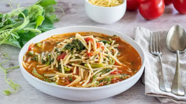 Piatto di pasta con i tenerumi asciutta, pomodoro e verdure fresche, pronto per essere gustato.