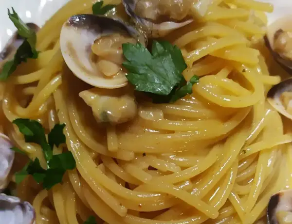 Spaghetti alle vongole cremosi come al ristorante, un piatto invitante con pasta dorata, vongole succulente e prezzemolo fresco.