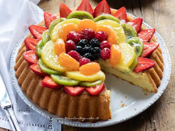 Una deliziosa crostata morbida alla frutta, con fragole, kiwi, mandarini e frutti di bosco su una base soffice e crema pasticcera.