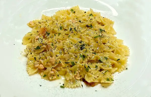 Farfalle condite con cubetti di salmone rosa, prezzemolo tritato e pepe nero. Un piatto di pasta al salmone invitante.