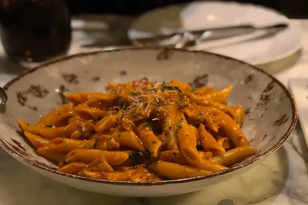 Penne al dente condite con una ricca crema di melanzane, guarnite con parmigiano e prezzemolo. Un piatto invitante per un pranzo gustoso.