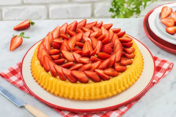 Deliziosa crostata di fragole, con una base dorata e un ripieno cremoso, ricoperta da fragole fresche affettate.