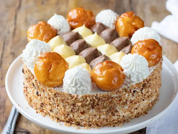 Una magnifica torta Saint Honoré, decorata con bignè caramellati, ciuffi di panna montata e crema pasticcera al cioccolato e vaniglia.