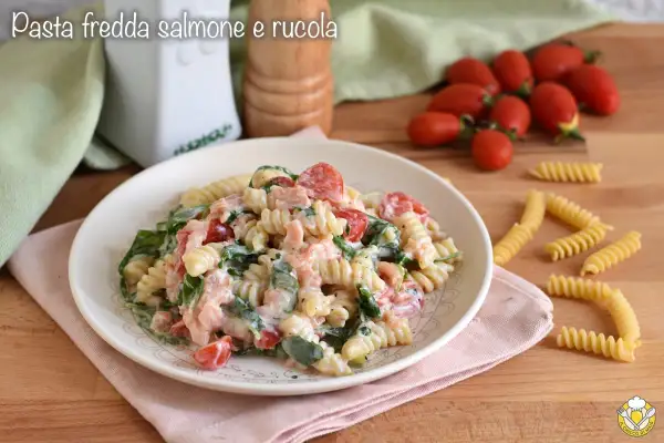 Piatto di pasta fredda con salmone, pomodorini e rucola, condita con una cremosa salsa.