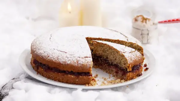 Torta di grano saraceno trentino con marmellata, spolverata di zucchero a velo, su un letto di neve e candele accese.