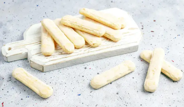 Savoiardi pronti per la ricetta del tiramisù, disposti su un tagliere bianco.