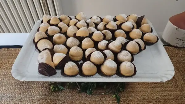 Dolcetti "tette delle monache" spolverati di zucchero a velo, un'antica ricetta che narra storie di conventi e sapori autentici.
