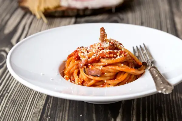 Un piatto di spaghetti alla amatriciana, con guanciale croccante e un tocco di cipolla per una ricetta originale.