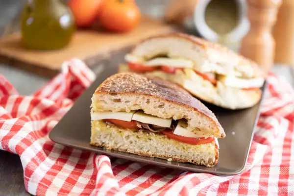 Pane cunzato con pomodoro, formaggio e acciughe, pronto per essere gustato.