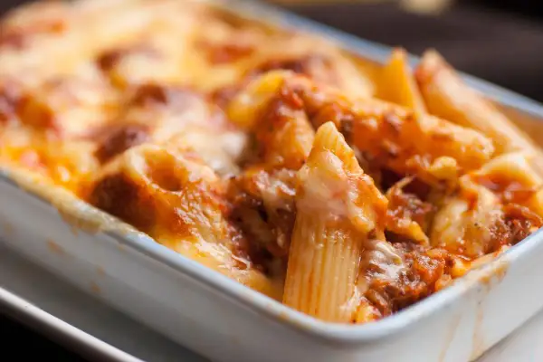 Un invitante piatto di pasta al forno, con penne ricoperte da un ricco sugo e abbondante formaggio fuso, pronto per essere gustato.