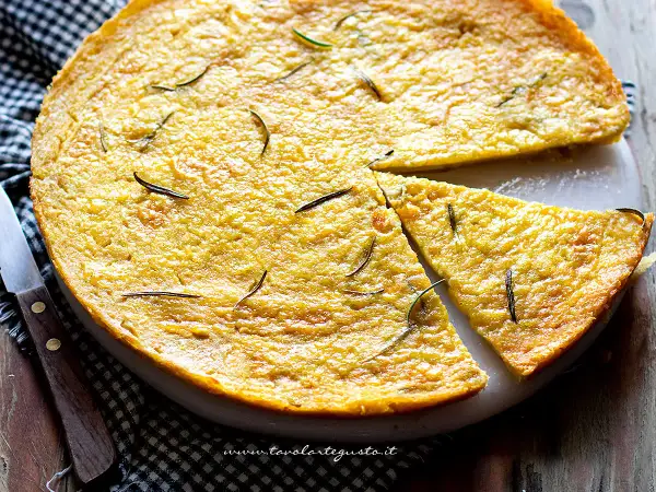 Dorata farinata di ceci in padella, guarnita con rosmarino fresco, pronta per essere gustata.