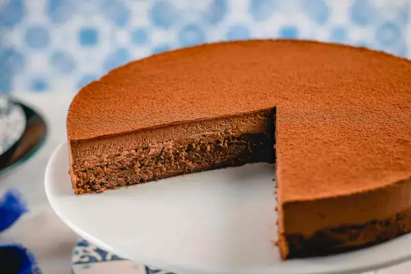 Una deliziosa torta Lisbona al cioccolato, con una soffice mousse e una base croccante, spolverata di cacao.
