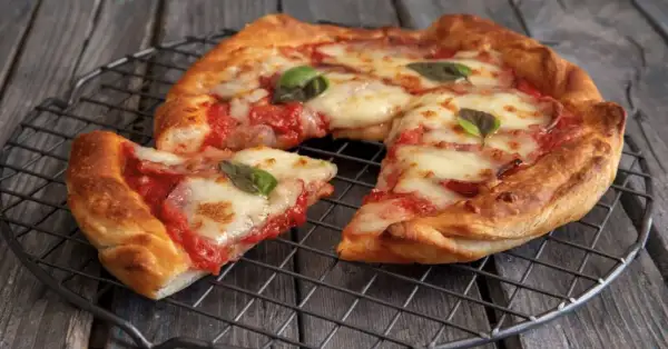 Pizza in friggitrice ad aria, croccante e filante, con pomodoro e mozzarella, guarnita con basilico fresco.